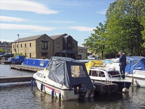 Brighouse, west yorkshire, united kingdom: 24 may 2017: a man on a houseboat surrounded by barges