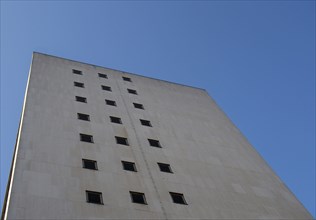 Perspective corner view of an old white 1960s concrete office block against a blue sky