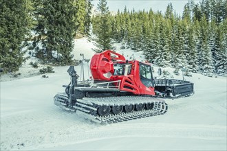 Winter image with a modern snow groomer machine, captured in the Austrian Alps, near the village