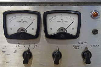 A close up of two old decibel meters on an old vintage reel to reel tape recorder with control