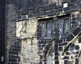 A full frame close up of ancient stonework stained glass windows and a sundial on the medieval