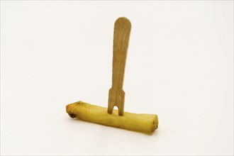 Wooden fries fork on a baked french fries on a white background