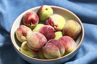 Vineyard peaches in a grey bowl on a blue background