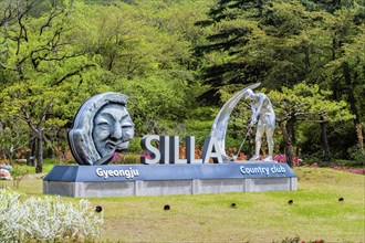 Silla Gyeongju Country Club sign with artistic sculptures, surrounded by lush greenery and trees in