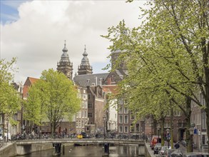 Picturesque canal scene with a bridge and historic buildings next to green trees in spring,