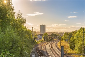 Landscape with the sun rays passing through the green trees and enlightening the railways and the