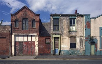 Derelict houses and abandoned commercial property on a residential street with boarded up windows