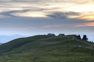 An impressive panorama of mountains with rocky peaks and dense forests under a cloudy sunset,