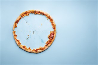 Pizza pepperoni leftovers top view on a blue background. Homemade pizza remainings and traces of