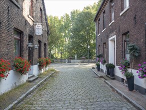 Picturesque cobblestone street with old houses and flowers, surrounded by trees, krudenburg, hünxe,