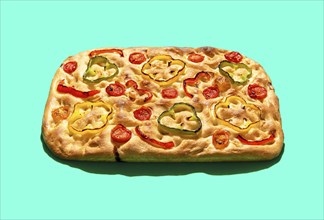 Homemade focaccia with vegetables and sourdough, in bright light minimalist on a green table.