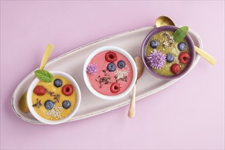 Three smoothie bowls with blueberries, raspberries, kiwi and peach