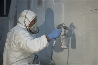 Tradesman sprays the fuselage on a Dornier 228 aircraft