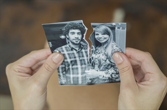 Great concept of divorce, betrayal, separation, woman hand ripping photo of the couple