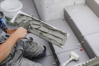 Tiler hands working on a new house entrance, local and professional handyman applying tiles to the