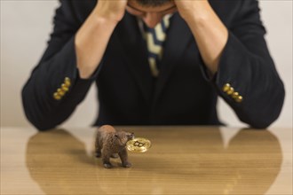 Young businessman trader depressed at bear figure and bitcoin. Bearish market concept