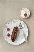 Eclair with chocolate ganache with raspberry topping and cream