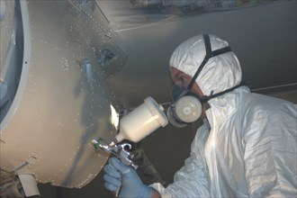 Tradesman sprays the engine on a Dornier 228 aircraft