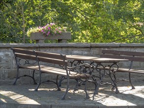 Park benches and a table next to a stone wall with flowers, on a sunny day, krudenburg, hünxe,