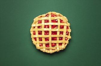 Strawberries and rhubarb pie with a lattice crust, above view on a green background. Top view with