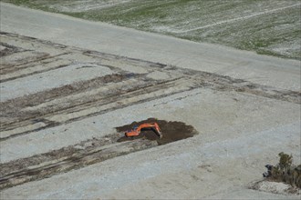 Digger excavating land to make humps and hollows for farmland, West Coast, South Island, New