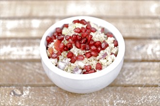 Quinoa salad with pomegranate seeds, radiccio, cucumber and olives on a light brown background