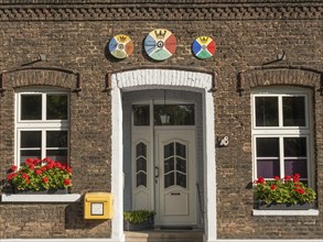 Entrance of a brick building with flowers in the window boxes and a yellow letter box, krudenburg,