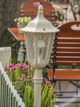 White lantern in the outdoor area of a restaurant with flowers and green furniture, spiekeroog,