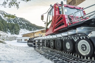 Tracked snow groomer car, parked near an alpine mansion, high in the Austrian Alps, near the