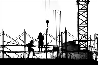 Construction workers and crane seen in outline