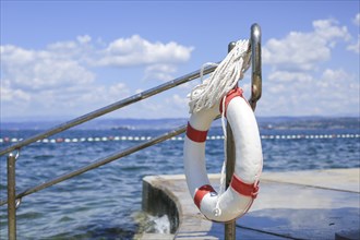 Emergency lifebuoy hanging on fence near sea at beach