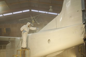 Tradesman sprays the fuselage on a Dornier 228 aircraft