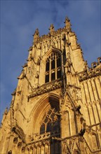 Side view of one of the towers at the front of york minster in sunlight against a blue cloudy sky