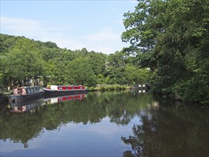 Traditional barges moored on the rochdale canal surrounded by calder valley countryside near hebden