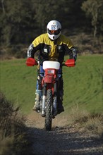 Female motorcyclist, standing in the rests, off-road, colourful clothes, red Honda