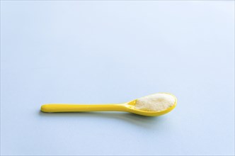Spoon with sugar close-up on a light blue background