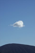 One small fluffy cloud over a hilltop