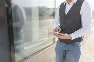 Young and Casual Businessman Using Tablet while Walking Outside of Office Building