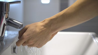 Coronavirus infection prevention. Person washing hands with soap and water, detail