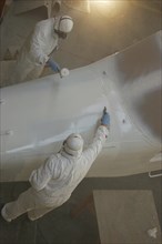 Tradesmen sprays the top of the nose on a Dornier 228 aircraft