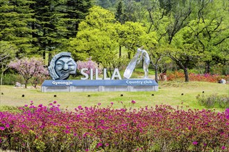 Silla Gyeongju Country Club sign surrounded by colorful flowers and green trees, indicating a