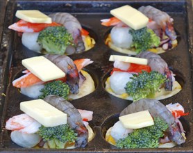 A street vendor prepares seafood, cheese and vegetables for baking