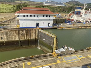 Industrial scene at a lock with a locomotive and a large white building. The sky is clear, panama