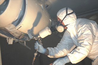 Tradesman sprays top coat on the top of the nose on a Dornier 228 aircraft