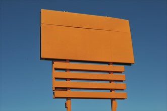 Blank orange billboard against blue sky