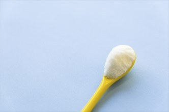 Spoon with sugar close-up on a light blue background
