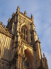 Side view of one of the towers at the front of york minster in sunlight against a blue cloudy sky