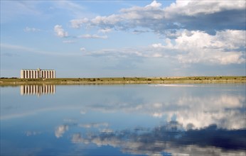 Corn Silos in South Africa, across a fresh water lake with blue skies and clouds, and a flock of