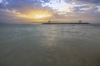 Beautiful seascape in the morning. Tropical sandy beach with breakwater and reflection of the sky