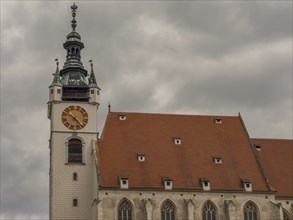 Church with a red roof and a Gothic clock tower under a cloudy sky, Dürnstein, Wachau, Danube,